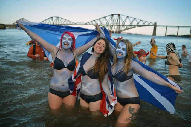Girls holding saltire flags join around a thousand New Year swimmers, many in costume, who braved freezing conditions in the River Forth in front of the Forth Rail Bridge during the annual Loony Dook Swim on January 1, 2013 in South Queensferry, Scotland. Thousands of people gathered last night to see in the New Year at Hogmanay celebrations in towns and cities across Scotland. (Photo by Jeff J. Mitchell)