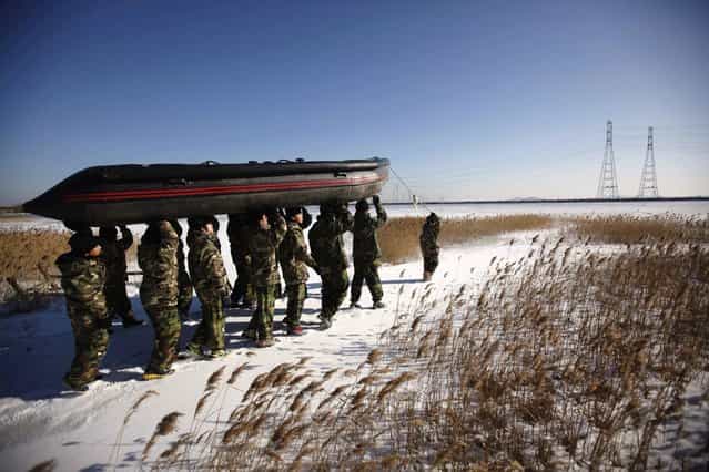 Students carry an inflatable boat during a winter military camp in Ansan, south of Seoul January 3, 2013. Hundreds of students between 11 and 17 years old attend winter boot camp training courses every year. The winter courses range from 4 to 14 days at the Blue Dragon Camp run by retired marines, which also offers summer boot camp for students. REUTERS/Kim Hong-Ji (SOUTH KOREA - Tags: EDUCATION SOCIETY MILITARY)