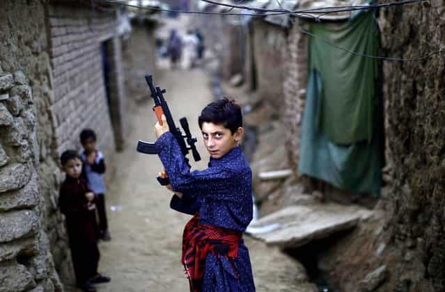 An Afghan refugee boy poses with a plastic rifle as he and other children celebrate the first day of the Eid al-Fitr festival, which marks the end of the Muslim fasting month of Ramadan, in a slum on the outskirts of Islamabad, Pakistan, August 20, 2012. Muslims around the world are celebrating Eid al-Fitr, marking the end of Ramadan, the Muslim calendar’s ninth and holiest month during which followers are required to abstain from food and drink from dawn to dusk. (Photo by Muhammed Muheisen/AP Photo)