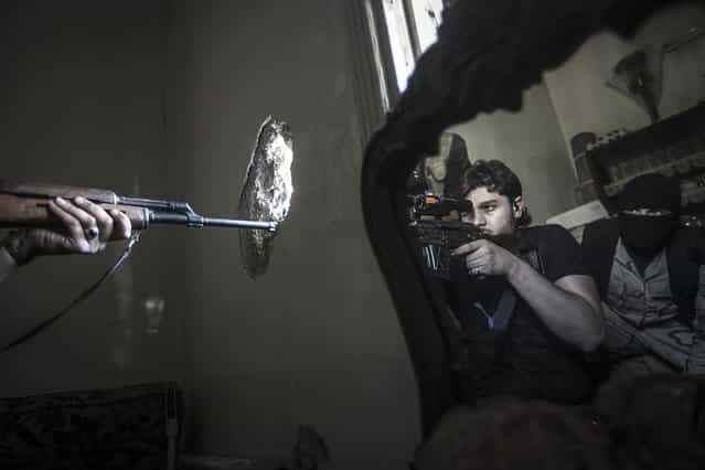 In this October 29, 2012 file photo, a rebel sniper aims at a Syrian army position, seen with another rebel fighter reflected in a mirror, in a residential building in the Jedida district of Aleppo, Syria. (Photo by Narciso Contreras/AP Photo)