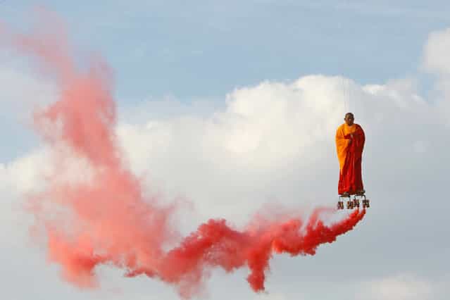 In this March 20, 2012 file photo, suspended by wires, Chinese artist Li Wei performs in the sky at La Villette in Paris. Wei’s work often depicts him in apparently gravity-defying situations. (Photo by Francois Mori/AP Photo)