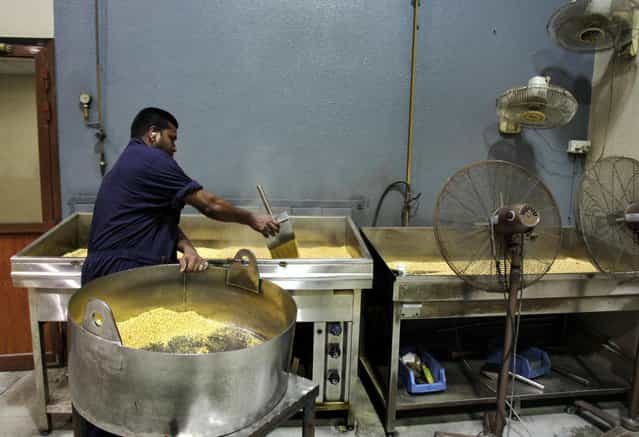 Steam rises from hot grains of gold after being melted and dropped into water as a technician pours the nuggets into a cooling container at the Emirates Gold company in Dubai, United Arab Emirates. One of the largest gold factory in the region, Emirates Gold has processed more than two million kg of gold, worth about 108 billion U.S. dollars, into gold bars, coins and medals since it was established in 1992, Mohamad Shakarchi, managing director of the company says. (Photo by Kamran Jebreili/AP Photo)