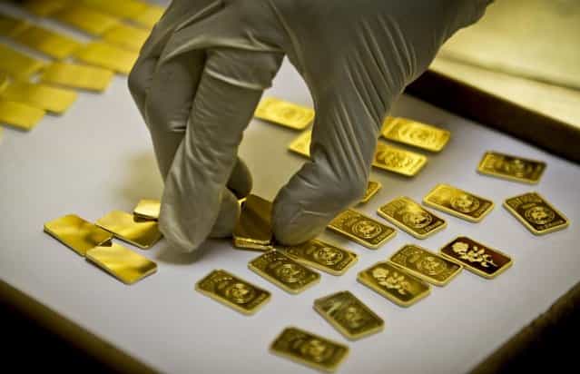 A gold press operator collects 10 gram gold blanks to press them with the logo of the Emirates Gold company in Dubai, United Arab Emirates. Gold prices remained relatively steady in 2012, close to $1,700 an ounce. (Photo by Kamran Jebreili/AP Photo)