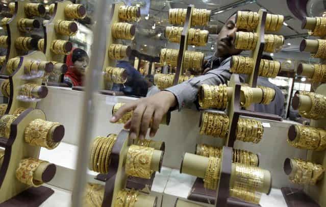 An Indian salesman collects a bangle to present to a customer at a jewelry shop in the gold suq in Dubai, United Arab Emirates. Dubai's tax-free status has made it one of the cheapest places in the world to buy gold and has also become a retail center with 600 shops selling gold – half of them crammed into the gold souq – drawing tourists, traders and local residents. (Photo by Kamran Jebreili/AP Photo)