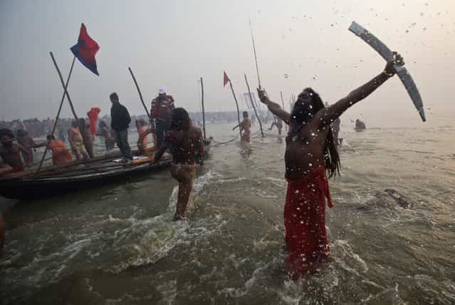 A Sadhu or a Hindu holy brandishes a sword as he attends the first [Shahi Snan] (grand bath) at the ongoing [Kumbh Mela], or Pitcher Festival, in the northern Indian city of Allahabad January 14, 2013. Upwards of a million elated Hindu holy men and pilgrims took a bracing plunge in India's sacred Ganges river to wash away lifetimes of sins on Monday, in a raucous start to an ever-growing religious gathering that is already the world's largest. (Photo by Ahmad Masood/Reuters)