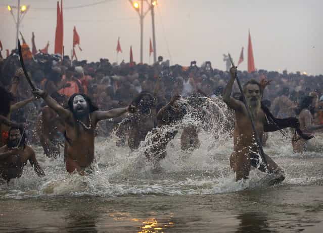 Indian Hindu holy men, or Naga Sadhus, run naked into the water at Sangam, the confluence of the Ganges, Yamuna and mythical Saraswati river, during the royal bath on Makar Sankranti at the start of the Maha Kumbh Mela in Allahabad, India, Monday, Jan. 14, 2013. Millions of Hindu pilgrims are expected to take part in the large religious congregation that lasts more than 50 days on the banks of Sangam which falls every 12 years. (Photo by Kevin Frayer/AP Photo)