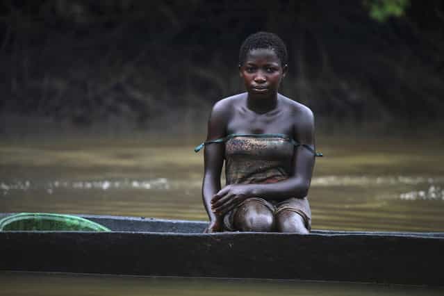 A young woman named Akpomene is pictured coated in oil stains as she sits in a canoe near river Nun in Nigeria's oil state of Bayelsa November 27, 2012. Akpomene fishes in the creek and sells the fish to help her family. She washes after fishing but has sticky rashes on her body. Thousands of people in Nigeria engage in a practice known locally as 'oil bunkering' - hacking into pipelines to steal crude then refining it or selling it abroad. The practice, which leaves oil spewing from pipelines for miles around, managed to lift around a fifth of Nigeria's two million barrel a day production last year according to the finance ministry. (Photo by Akintunde Akinleye/Reuters)