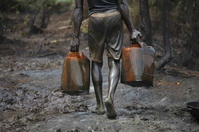 A man works at an illegal oil refinery site near river Nun in Nigeria's oil state of Bayelsa November 27, 2012. Thousands of people in Nigeria engage in a practice known locally as 'oil bunkering' - hacking into pipelines to steal crude then refining it or selling it abroad. The practice, which leaves oil spewing from pipelines for miles around, managed to lift around a fifth of Nigeria's two million barrel a day production last year according to the finance ministry. (Photo by Akintunde Akinleye/Reuters)