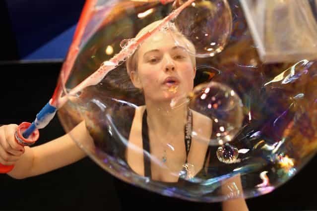 A woman on a trade stand blows bubbles during the 2013 London Toy Fair at Olympia Exhibition Centre on January 22, 2013 in London, England. The annual fair which is organised by the British Toy and Hobby Association, brings together toy manufacturers and retailers from around the world. (Photo by Dan Kitwood)