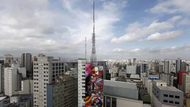 Brazilian graffiti artist Eduardo Kobra (C) puts the final touches to his piece of art in tribute to Brazilian architect Oscar Niemeyer, next to his assistants, at the financial center on Sao Paulo's Avenida Paulista January 22, 2013. Kobra created the 56-metre (61-yard) tall graffiti artwork as a tribute to Niemeyer, one of the 20th century's most influential modernist architects. Niemeyer died in December 2012, aged 104. REUTERS/Nacho Doce (BRAZIL - Tags: SOCIETY CITYSCAPE)