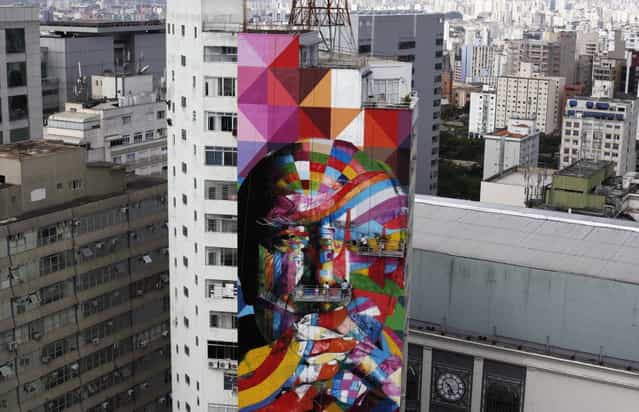 Brazilian graffiti artist Eduardo Kobra (C) puts the final touches to his piece of art in tribute to Brazilian architect Oscar Niemeyer, next to his assistants, at the financial center on Sao Paulo's Avenida Paulista January 22, 2013. Kobra created the 56-metre (61-yard) tall graffiti artwork as a tribute to Niemeyer, one of the 20th century's most influential modernist architects. Niemeyer died in December 2012, aged 104