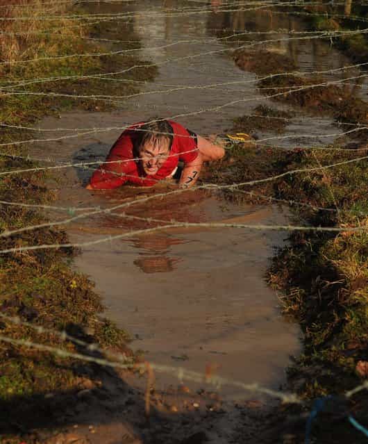 A competitor crawls under barbed wire during the Tough Guy Challenge endurance race on January 27, 2013 in Telford, England. Every year thousands of people run the 8 mile assault course which involves freezing temperatures, fire and ice. (Photo by Michael Regan)