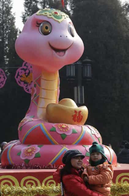 A mother holding her child poses for a photo next to a snake sculpture at a temple fair to celebrate the Chinese Lunar New Year at Ditan Park (the Temple of Earth), in Beijing, February 9, 2013. The Lunar New Year, or Spring Festival, begins on February 10 and marks the start of the Year of the Snake, according to the Chinese zodiac. (Photo by Jason Lee/Reuters)