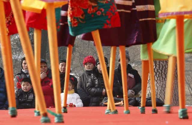 People watch Chinese folk artists on stilts during their performance at Longtan Park in Beijing February 9, 2013. The Lunar New Year, or Spring Festival, begins on February 10 and marks the start of the Year of the Snake, according to the Chinese zodiac. (Photo by Kim Kyung-Hoon/Reuters)