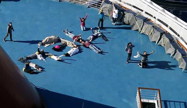 Passengers spell out the word [HELP] aboard the disabled Carnival Lines cruise ship Triumph as it is towed to harbor, February 14, 2013. (Photo by Gerald Herbert/Associated Press)