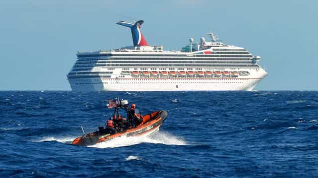 A small boat belonging to the Coast Guard Cutter Vigorous patrols near the cruise ship Carnival Triumph in the Gulf of Mexico on February 11, 2013. The Carnival Triumph has been floating aimlessly about 150 miles off the Yucatan Peninsula since a fire erupted in the aft engine room early Sunday, knocking out the ship's propulsion system. No one was injured and the fire was extinguished. (Photo by Lt. Cmdr. Paul McConnell/U.S. Coast Guard)