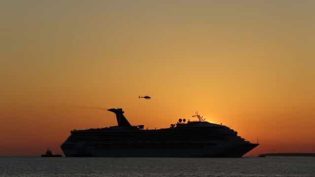 The sun sets as the Carnival Triumph is towed into Mobile Bay near Dauphin Island, February 14, 2013. (Photo by Dave Martin/Associated Press)