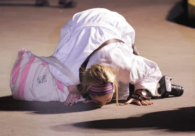 Kendall Jenkins of Houston kisses the ground after stepping off the Carnival ship Triumph (Photo by AP Photo)