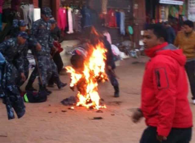 An exiled Tibetan monk sets himself on fire at Boudhanath Stupa in Kathmandu on February 13, 2013. A Tibetan monk doused himself in petrol in a Kathmandu restaurant and set himself on fire, marking the 100th self-immolation bid in a wave of protests against Chinese rule since 2009. Police in the Nepalese capital told AFP that the exile had burned himself in an eatery near Kathmandu's Boudhanath Stupa, one of the world's holiest Buddhist shrines, terrifying tourists who were having breakfast. (Photo by STR/AFP Photo)