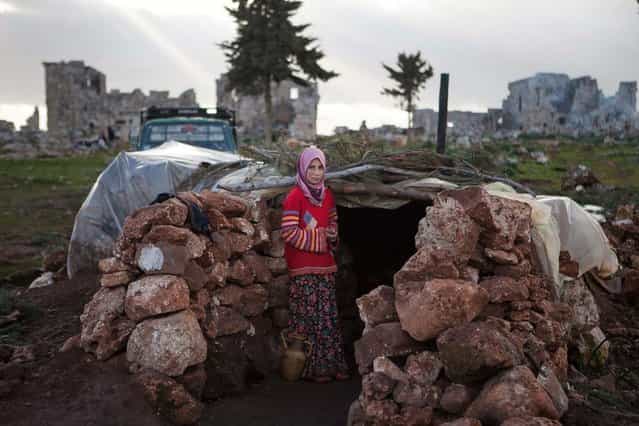 A Syria girl stands at the entrance of a makeshift home set up in the catacombs of the ruins of an ancient building in the ancient Roman city of of Serjilla, in northwestern Syria, on February 11, 2013, after fleeing the fighting between rebel forces and pro-government troops in the town of Kfar Nubul, in the northwestern province of Idlib. (Photo by Daniel Leal-Olivas/AFP Photo)