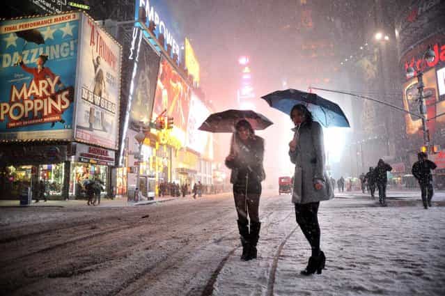 Two girls look for a taxi in the snow in Times Square in New York on February 8, 2013 during a storm affecting the northeast US. The storm was forecast to bring the heaviest snow to the densely-populated northeast corridor so far this winter, threatening power and transport links for tens of millions of people and the major cities of Boston and New York. New York and other regional airports saw more than 4,500 cancellations ahead of what the National Weather Service called [a major winter storm with blizzard conditions] along most of the region's coastline. (Photo by Mehdi Taamallah/AFP Photo)