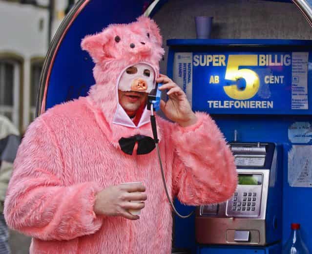 A man dressed as a pig uses a phone during the start of the street-carnival with its tradition of fools entering the town halls and women cutting off men's ties with scissors on carnival's so called [Old Women's Day] in Cologne, Germany, on February 7, 2013. (Photo by Frank Augstein/Associated Press)