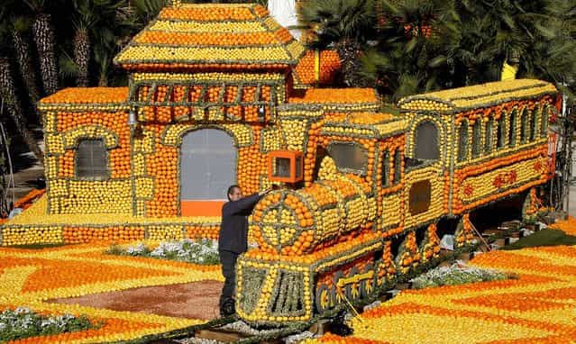 A worker puts the finishing touches on a train made with lemons and oranges during the 80th Lemon festival in Menton on February 15, 2013. (Photo by Lionel Cironneau/Associated Press)