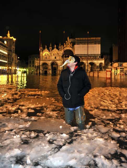 A man wearing a carnival mask wades through high water with floating ice in a flooded St. Mark's Square, in Venice, Italy, early Tuesday, Feb. 12, 2013. The phenomenon of high water, which floods the Venice lagoon, occurs mainly between autumn and spring when tides are reinforced by seasonal winds. The recent snow falls and low temperatures formed ice blocks in the water. (AP Photo/Luigi Costantini)
