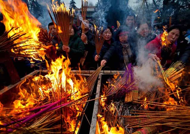 Temple goers burn incense as they pray for health and fortune on the first day of the Chinese Lunar New Year at Yonghegong Lama Temple in Beijing, on February 10, 2013. Millions across China are celebrating the arrival of the Lunar New Year, the Year of the Snake, marked with a week-long Spring Festival holiday. (Photo by Andy Wong/Associated Press)