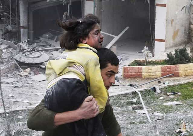 A man carries his sister, who was wounded in a government air strike, in Aleppo, Syria, on February 3, 2013. The Britain-based activist group, Syrian Observatory for Human Rights, said government troops bombarded a building in Aleppo's rebel-held neighborhood that killed more than10 people, including at least five children. (Photo by Abdullah al-Yassin/Associated Press)
