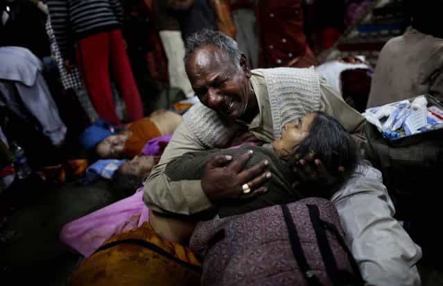 A man weeps as he holds his wife who was killed in a stampede on a railway platform at the main railway station in Allahabad, India, on February 10, 2013. At least ten Hindu pilgrims attending the Kumbh Mela were killed and more then thirty were injured during a stampede on an overcrowded staircase. (Photo by Kevin Frayer/Associated Press)
