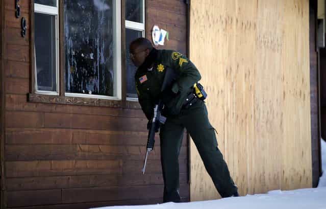 San Bernardino County Sheriff's officer Ken Owens searches a home for former Los Angeles police officer Christopher Dorner in Big Bear Lake on February 10, 2013. The hunt for Dorner, suspected in three killings, entered its fourth day, a day after the police chief ordered a review of the disciplinary case that led to the fugitive's firing and new details emerged of the evidence he left behind. (Photo by Jae C. Hong/Associated Press)