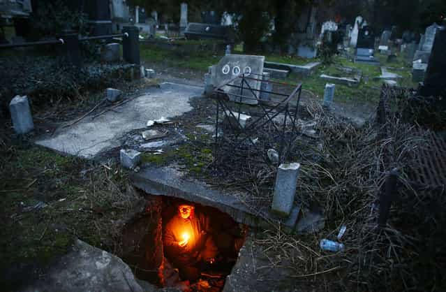 Bratislav Stojanovic, a homeless man, holds candles as sits in a tomb where he lives in southern Serbian town of Nis February 9, 2013. Stojanovic, 43, a Nis-born construction worker never had a regular job. He first lived in abandoned houses, but about 15 years ago he settled in the old city cemetery. (Photo by Marko Djurica/Reutars)