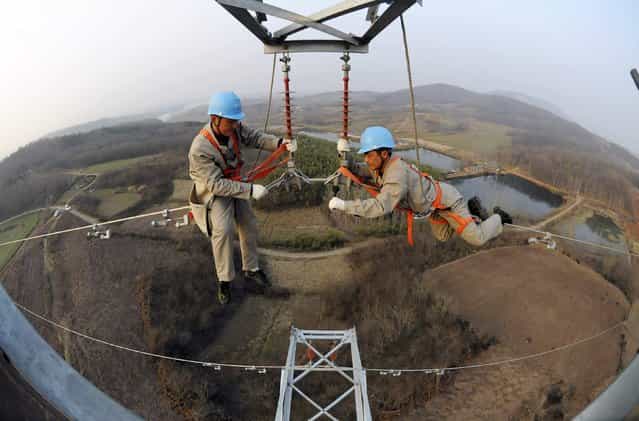 Workers check on electricity pylon situated amid farmlands in Chuzhou, Anhui province, February 5, 2013. A leading think tank of China predicted that China's GDP will grow in 2013 at a rate of 8.4 percent, up by 0.6 percentage points from that of 2012, Xinhua News Agency reported. (Photo by China Daily/Reuters)
