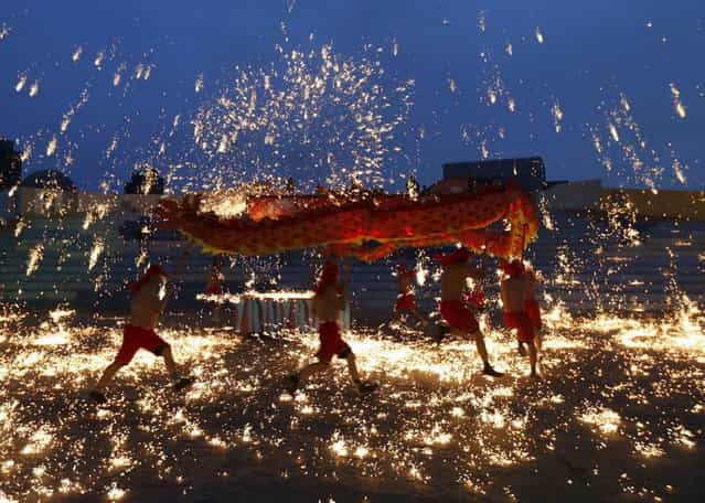 Dancers perform a fire dragon dance in the shower of molten iron spewing firework-like sparks during a folk art performance to celebrate traditional Chinese Spring Festival at an amusement park in Beijing February 10, 2013. The Lunar New Year, or Spring Festival, begun on February 10 and marked the start of the Year of the Snake, according to the Chinese zodiac. (Photo by Kim Kyung-Hoon/Reuters)