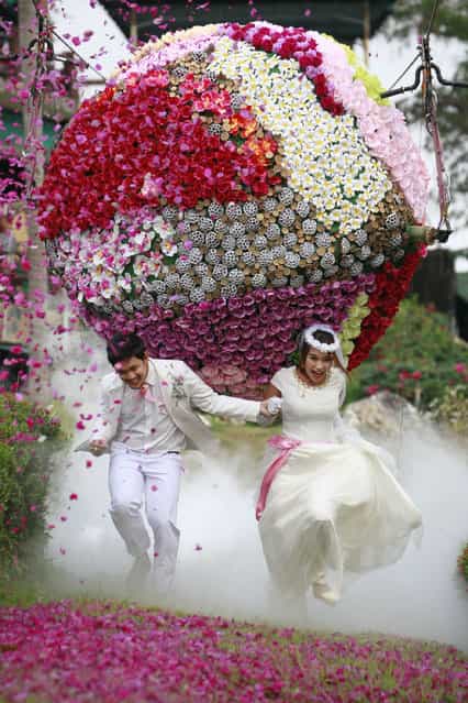 Prasit Rangsitwong, left, and Varutton Rangsitwong run away from a giant flower ball as a part of an adventure-themed wedding ceremony in Prachinburi province, Thailand, Wednesday, February 13, 2013, on the eve of Valentine's Day. (Photo by Wason Wanichakorn/AP Photo)