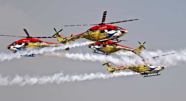 Indian Air Force helicopters cross paths while performing an aerobatic flight on the second day of the Aero India 2013 at Yelahanka air base in Bangalore, India, on February 7, 2013. More than 600 aviation companies along with delegations from 78 countries are participating in the five-day event. (Photo by Aijaz Rahi/Associated Press)