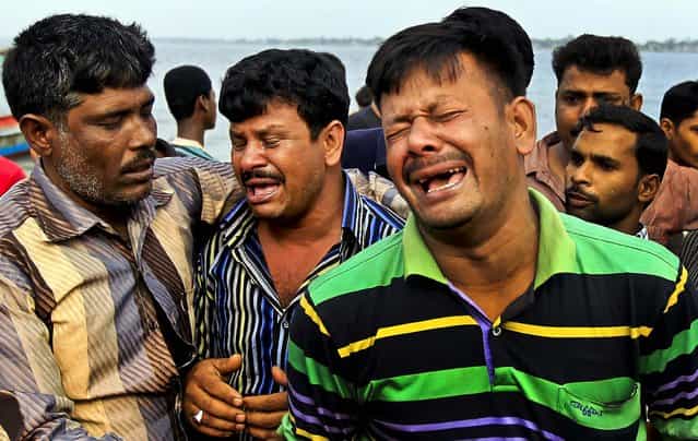 Men mourn the victims of a ferry that capsized on the banks of the Meghna River on February 8, 2013.The passenger ferry capsized after colliding with another ship on a river dumping as many as 100 people into the water. (Photo by A.M. Ahad/Associated Press)