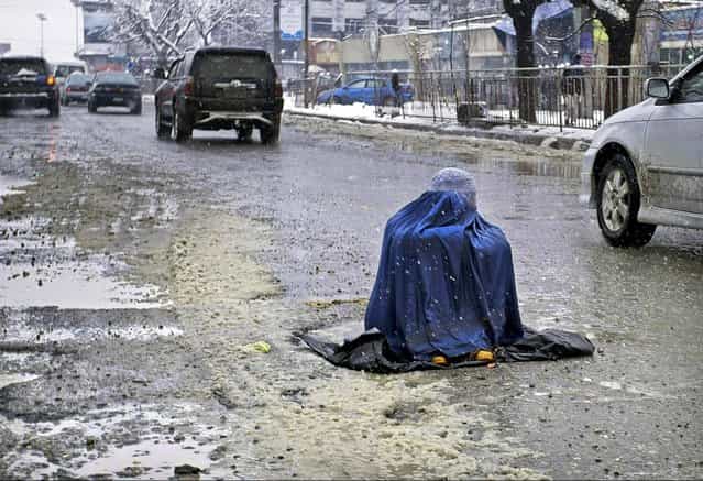 A woman sits in a street begging for money from motorists in Kabul, Afghanistan, on February 4, 2013. (Photo by Musadeq Sadeq/Associated Press)