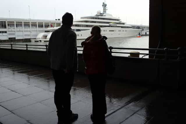 A couple looks out at the Eclipse, reported to be the largest private yacht in the world, which is docked at a pier in New York on February 19, 2013 in New York City. The boat, which measures 557ft in length and is estimated to cost 1.5 billion US dollars, is owned by Russian billionaire Roman Abramovich and arrived into New York on Wednesday. (Photo by Spencer Platt)