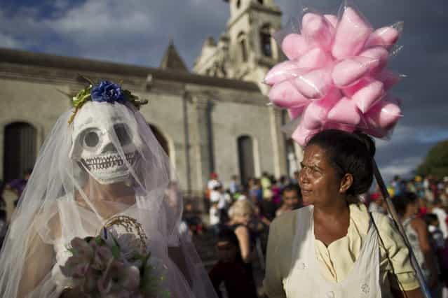A street vendor, right, looks at a disguised reveler during celebrations marking the 9th International Poetry Festival honoring Nicaraguan poet, priest and former Nicaragua's Culture Minister, Ernesto Cardenal, not in picture, in Granada, Nicaragua, Wednesday, Feb 20, 2013. The festival is attended by more than 300 poets from some 60 countries. (Photo by Esteban Felix/AP Photo)