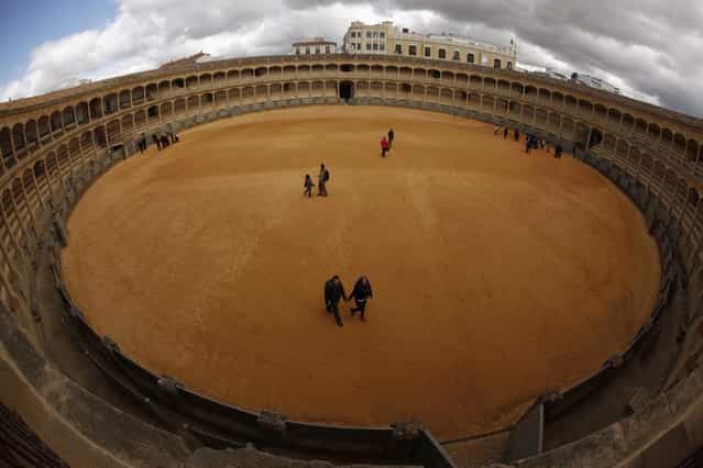 Tourists walk on the arena at the bullring in Ronda, near Malaga February 12, 2013. Ronda is considered one of the cradles of modern bullfighting emerged in the eighteenth century. Spain's parliament voted on Tuesday to consider protecting bullfighting as a national pastime, angering animal rights campaigners and politicians in two regions where the sport is banned. Picture taken with a fisheye lens. (Photo by Jon Nazca/Reuters)