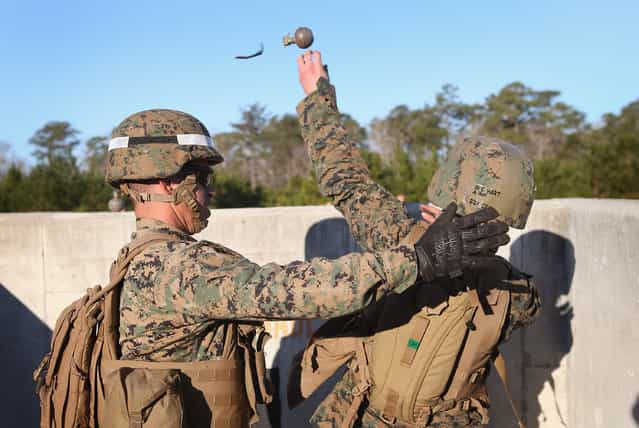 Sgt. Daniel Pettway (L) of Jacksonville, NC instructs Pfc. Shaina Hart of Floydada, TX the proper technique for throwing a hand grenade during Marine Combat Training (MCT) on February 21, 2013 at Camp Lejeune, North Carolina. Since 1988 all non-infantry enlisted male Marines have been required to complete 29 days of basic combat skills training at MCT after graduating from boot camp. MCT has been required for all enlisted female Marines since 1997. About six percent of enlisted Marines are female. (Photo by Scott Olson)