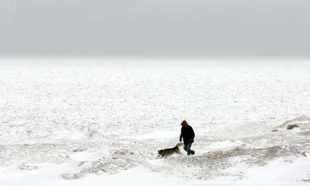 A man walks with his dog next to snow-covered Lake Michigan in Chicago, February 22, 2013. Gusty winds and iced-over roadways made for treacherous Midwest travel Friday as a major winter storm headed east over the Great Lakes. (Photo by Nam Y. Huh/Associated Press)