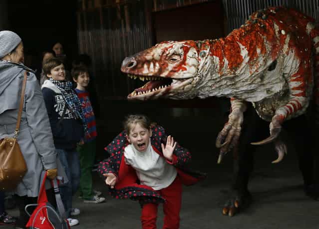 Children react as a carnivorous theropod known as the Australovenator dinosaur walks through crowds along the Southbank, in London, Monday, February 18, 2013. The dinosaur is one of many that can be visited at the Erth's Dinosaur Petting Zoo, visiting from Australia, the creatures can be touched and fed at the Southbank Centre. (Photo by Kirsty Wigglesworth/AP Photo)