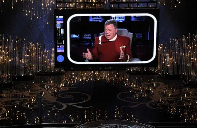 Host Seth MacFarlane, lower left, speaks to actor William Shatner, on screen, during the opening moments of the awards show, February 24, 2013. (Photo by Chris Pizzello/Invision)