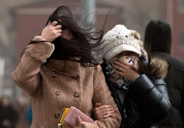 Chinese women cover their face as they brace through strong wind on a street as capital city is hit by sand storm in Beijing Thursday, February 28, 2013. (Photo by Andy Wong/AP Photo)