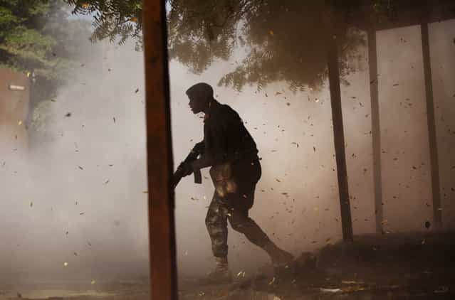 A Malian soldier takes cover amid a cloud of leaves and dust, after a rocket propelled grenade was fired by his comrades in Gao, on February 21, 2013. (Photo by Joe Penney/Reuters/The Atlantic)