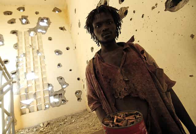 A man collects spent cartridge cases at a damaged police station one day after Islamist gunmen battled French and Malian troops, on February 11, 2013 in Gao. (Photo by Pascal Guyot/AFP Photo/The Atlantic)