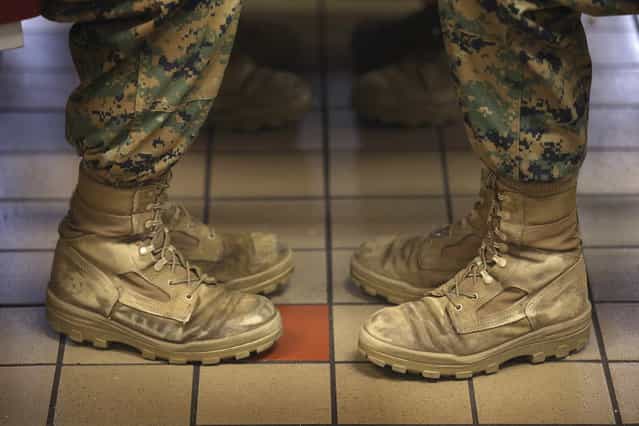 Female Marine recruits sit with their feet at a 45 degree angle, the same angle they are at while standing at the position of attention, while having lunch during boot camp on February 26, 2013 at MCRD Parris Island, South Carolina. Female enlisted Marines have gone through recruit training at the base since 1949. About 11 percent of female recruits who arrive at the boot camp fail to complete the training, which can be physically and mentally demanding. On January 24, 2013 Secretary of Defense Leon Panetta rescinded an order, which had been in place since 1994, that restricted women from being attached to ground combat units. (Photo by Scott Olson/AFP Photo)